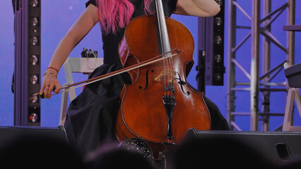 Cellist with vibrant pink hair playing cello during a live music concert © Довидович Михаил