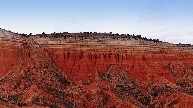 Distancing from layered ridged red rocks with scarce vegetation. Amazing geological formations in Teruel, Spain.