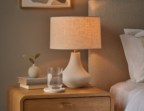 A stylish bedside table featuring a lamp and a glass of water.