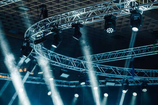 Stage lighting illuminating metal truss structure during a live concert or event, creating dynamic beams in the dark venue
