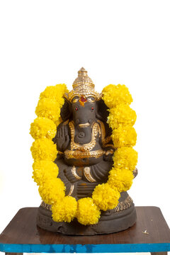 Ganesha idol decoration with gold colored coating and yellow marigold garland for Hindu rituals