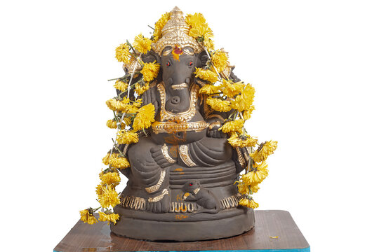 Ganesha idol decoration with gold colored coating and yellow marigold garland for Hindu rituals