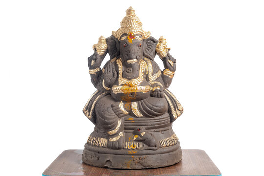 Clay Ganesha idol decorated in gold color for home decoration and spiritual worship.