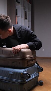 Vertical video man struggling to close an overpacked suitcase, symbolizing the challenges of preparing for a long journey or moving, highlighting themes of travel, packing, and relocation