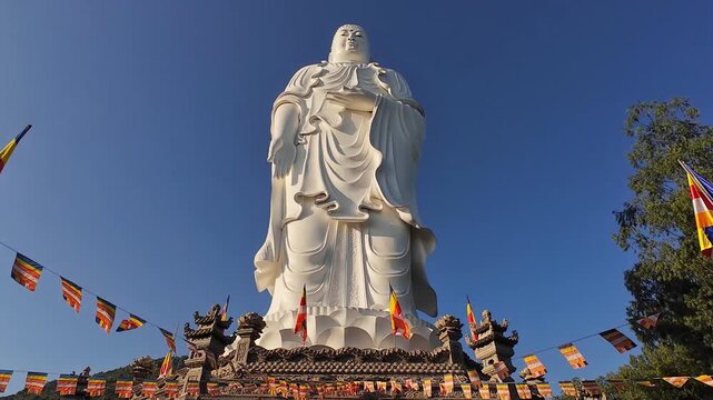 Standing Buddha statue at Tong Lam Son Temple in Nha Trang, Vietnam against a clear sky. Peaceful spiritual landmark with detailed sculpture and calm atmosphere.