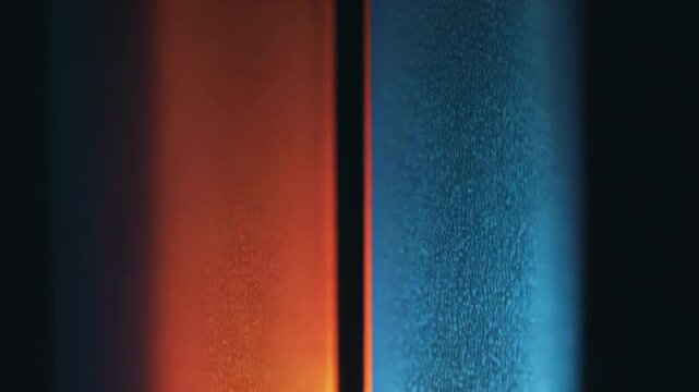 Abstract light beams are separating two distinct areas of vivid orange and blue, creating a vibrant color contrast and dynamic glow effect across a dark background