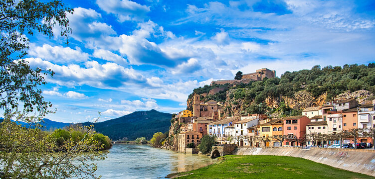Panorama of the town of Miravet and the river Ebro in Tarragona province, Spain. Colorful houses at the foot of a forested hill, dominated by a medieval castle of the Knights Templar.
