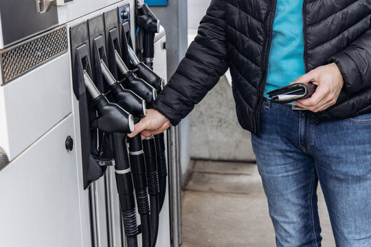 Man holding fuel nozzle at gas station refueling car
