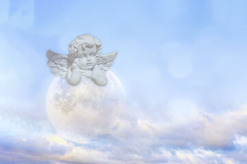 Naklejka premium An angel statue rests above the moon in clouds