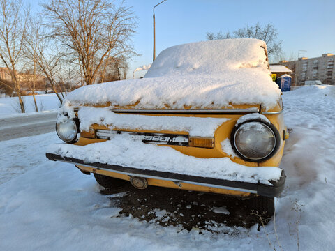 Old car Zaporozhets, soviet automobile is parked on snow-covered parking lot