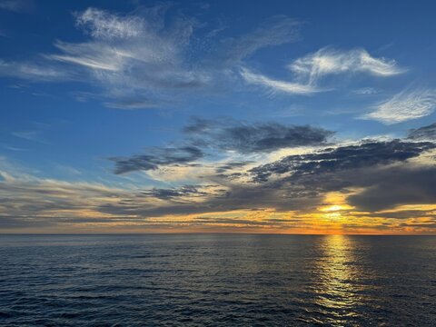 Calm ocean and sunset sky clouds.