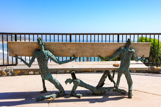 Artistic bronze figures holding a wooden bench on the cliffs of Laguna Beach, California. &ldquo;Support&rdquo; was created by Laguna Beach artist Louis Longi 