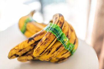 Naklejka premium Roseland, USA - March 21, 2025: Yellow ripe banana, bananas bunch by Dole brand company on home kitchen white table organic usda certified