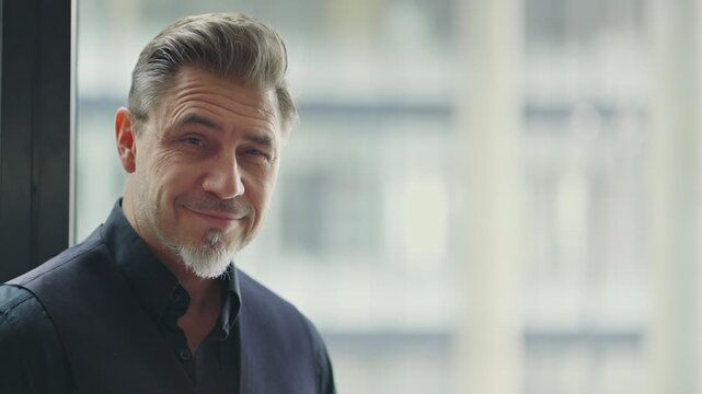 Business portrait - businessman standing in office, smiling. Happy middle aged, mid adult man in black jacket.