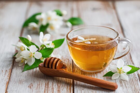 Jasmine tea with honey and jasmine flowers on wooden table.