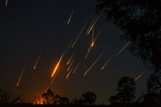 Dramatic meteor shower streaks across the night sky with fiery trails.