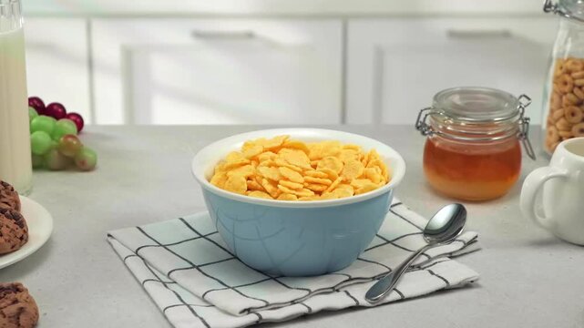 Healthy breakfast cereal, corn flakes, bowl with milk, honey, nuts and fruits on kitchen table