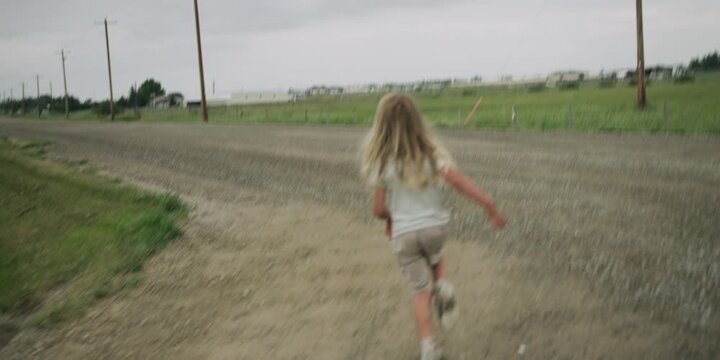 Young boy standing on a gravel road looking away from camera