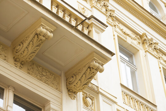 Ornate architectural details of a historic building featuring decorative cornices and intricate carvings on the facade, showcasing classical design elements in a city setting
