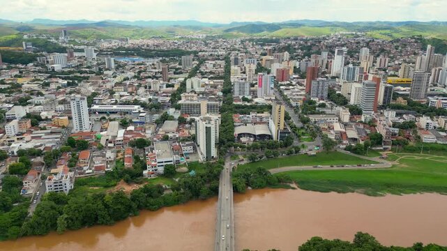 Aerial drone flyover of the city of Governador Valadares, Minas Gerais, Brazil, located along the banks of the Doce river. The footage captures the cityscape, surrounding riverfront, and key landmarks