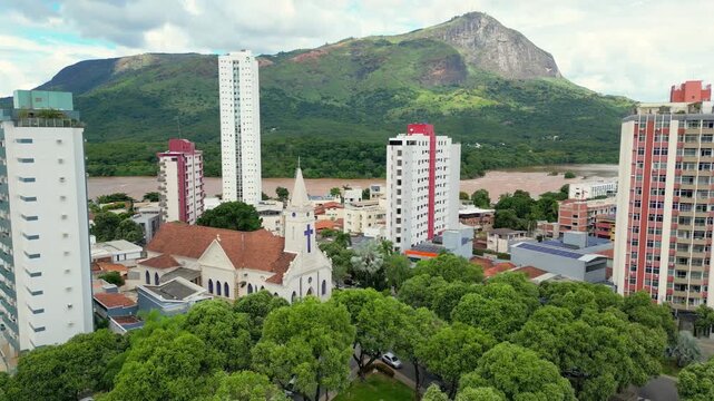 Aerial drone flyover of the city of Governador Valadares, Minas Gerais, Brazil, located along the banks of the Doce river. The footage captures the cityscape, surrounding riverfront, and key landmarks