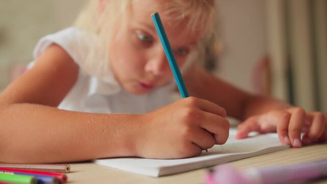 Girl concentrating on writing exercise at home, close-up. preschool education concept