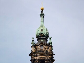 Decorative spire exists. Elaborate steeple with gilded accents under cloudy sky and ringing bell © Vladimir