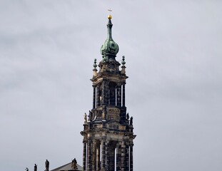 Vertical structure with weathered features. Sculpted tower with layered cornices and verdigris spire © Vladimir