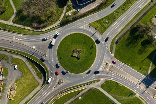 Aerial top down view of Seacroft Leeds roundabout with cars moving along marked lanes and central grass island showing transport layout and road infrastructure in daylight conditions in spring time