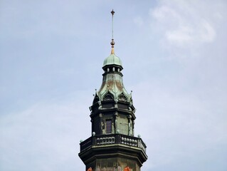Ancient municipal tower adorned with gilded accents and layered spires visible against overcast sky © Vladimir