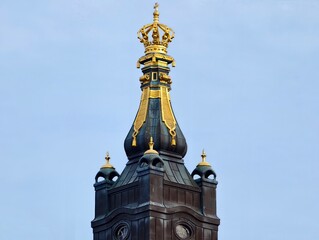 Shiny crown ornament. Elaborate gilded crown sculpture on turrets highlighting royal craftsmanship © Vladimir