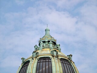 Colorful metal structure among clouds. Ornate copper dome with arched windows against clear blue sky © Vladimir