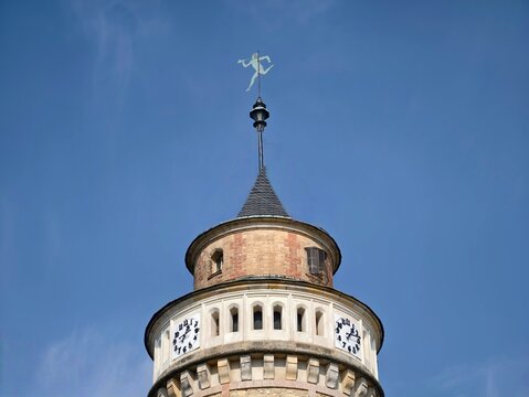 Clock tower skyward. Circular clock faces under clear sky with shining weather vane and elegant crown