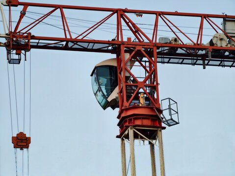 Heightened view of construction crane operator. Silhouette of heavy crane with safety gear visible
