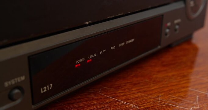 Close-up view of VHS tape exiting video cassette recorder. Retro media device and pre-digital consumer video technology
