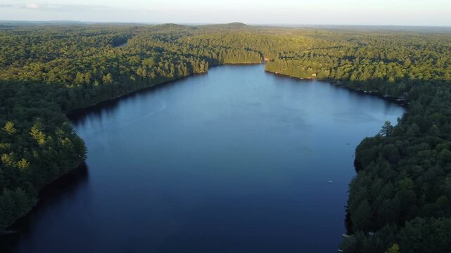 Flying over Buckskin Lake in summer before sunset. Aerial above lakeside cottages among wilderness of crown land located in the Tory Hill, Halliburton Highlands East, Ontario, Canada.