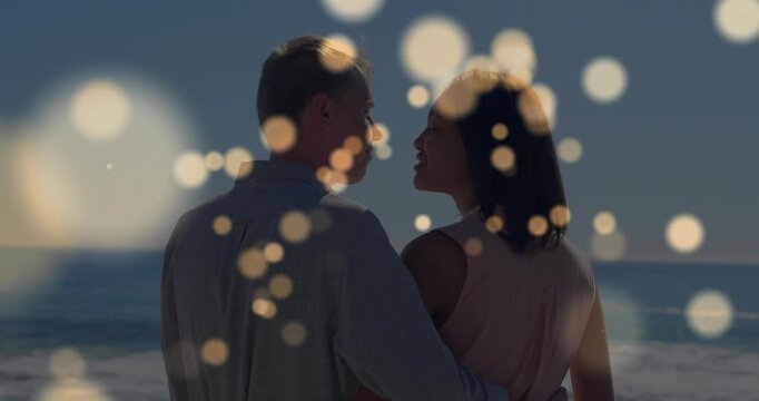 Couple standing sea rail, turning, leaning and kissing sparking moving bokeh hiding faces for ads