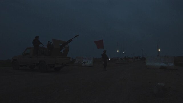 Soldiers and an armed technical pickup truck securing a military checkpoint during the night