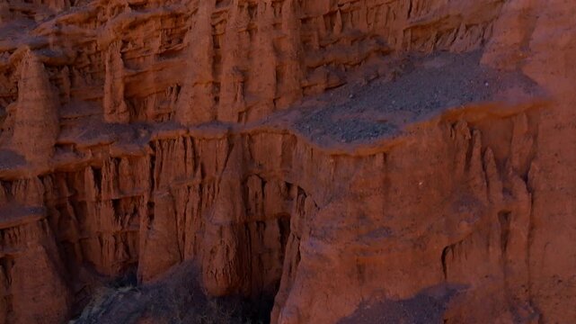 Dramatic ascending reveal aerial view of eolian castle formations in Kyrgyzstan, closeup to a cliff to view from above.