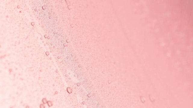Water drops falling and draining on pink background, closeup