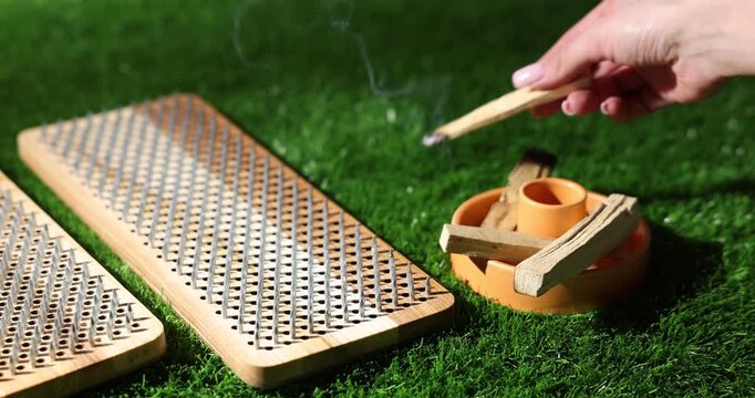 Woman with Sadhu boards and Palo Santo sticks on green grass, closeup