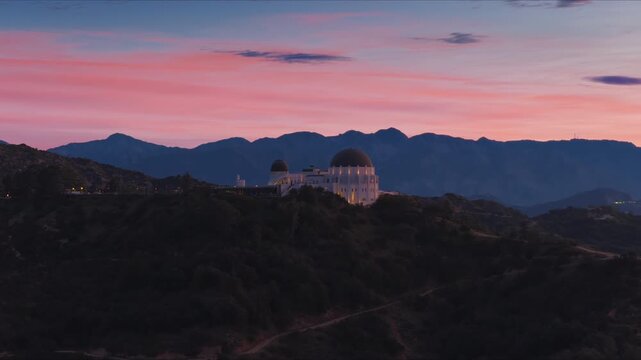 Los Angeles, California USA - FEBRUARY 27, 2026: Griffith Observatory before sunrise with soft dawn colors pink sky silhouettes of mountains and quiet early morning atmosphere over the city.