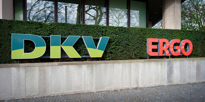 Cologne, Germany March 21 2026: Outdoor signage featuring the colorful logos of DKV and ERGO insurance groups on a hedge in front of a modern office complex