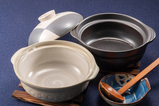 白と黒の土鍋・木のスプーンと小皿を紺色背景に並べた和食器の物撮り