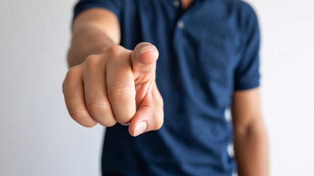 A man points directly at the camera with his index finger extended.