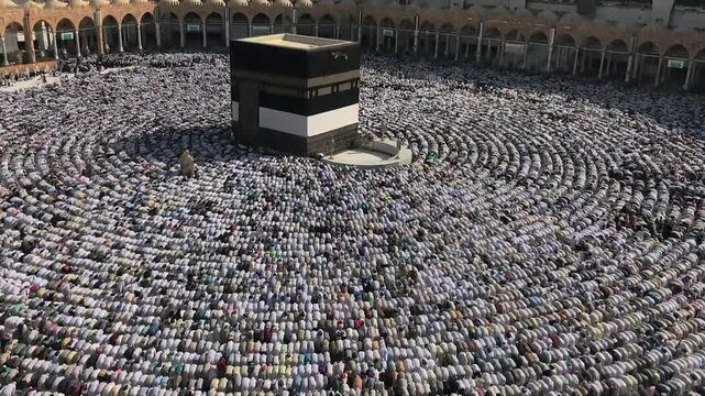 Thousands of muslim pilgrims praying in circular rows around the Kaaba in Mecca, Saudi Arabia