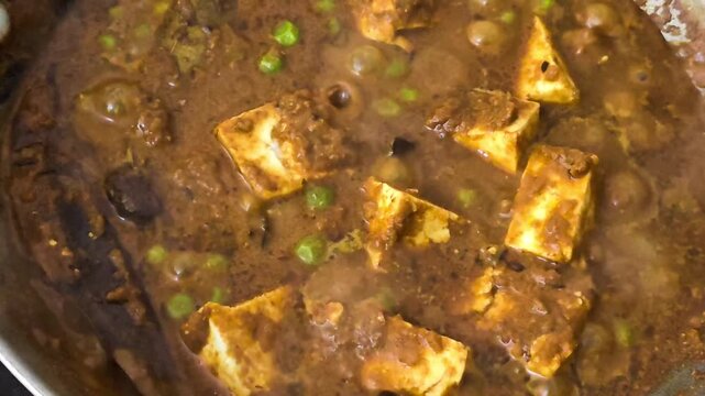 Close up of delicious indian matar paneer curry boiling and simmering in a cooking pan