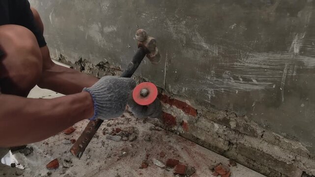 Manual Worker Using Hammer to Chip Away Concrete Wall