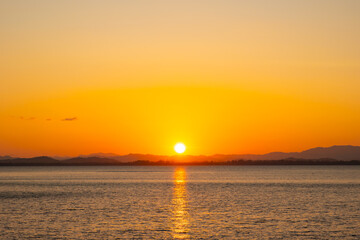 Obraz premium nature sky breathtaking golden sunset over a calm ocean, with the entire sky and water bathed in brilliant shades of yellow and orange. Streaky clouds enhance the dramatic display 