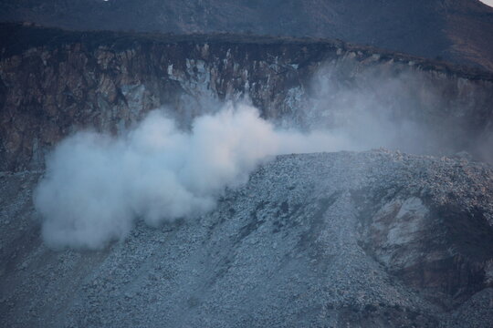 A massive dust cloud erupts from a controlled explosion at a marble quarry in Buner, Pakistan, showing the raw power of industrial mining against a rugged mountain cliff.